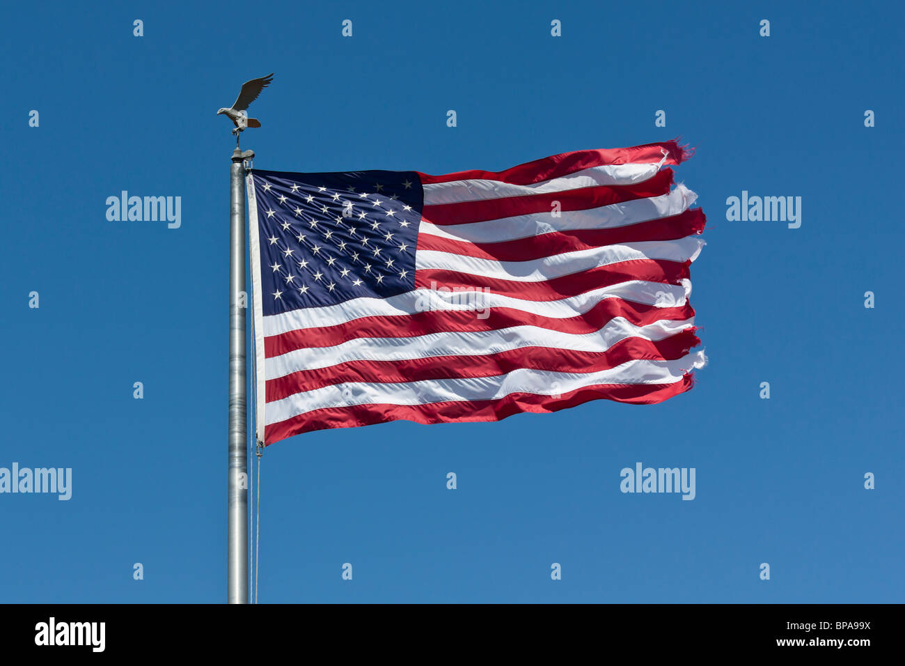 The US flag on a stand pole with silver Eagle against blue sky ...