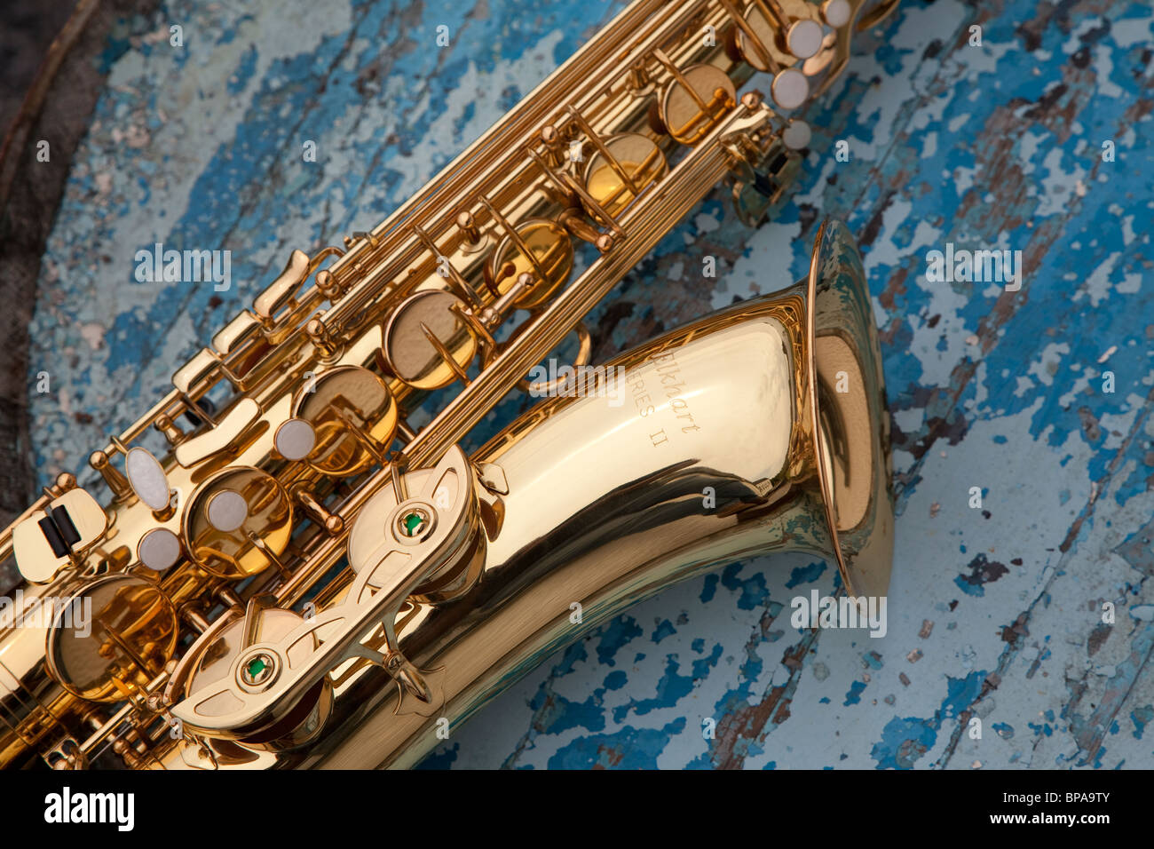 A new saxophone contrast against the flaking blue paint of a whisky cask. Stock Photo