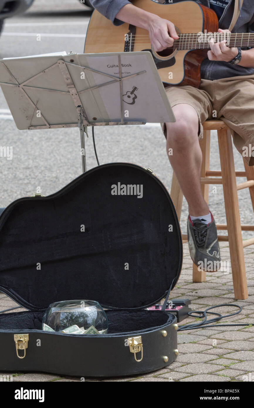 A street performer young man playing on a acoustic guitar with open case for guitar with money in USA US lifestyle scenes events vertical hi-res Stock Photo