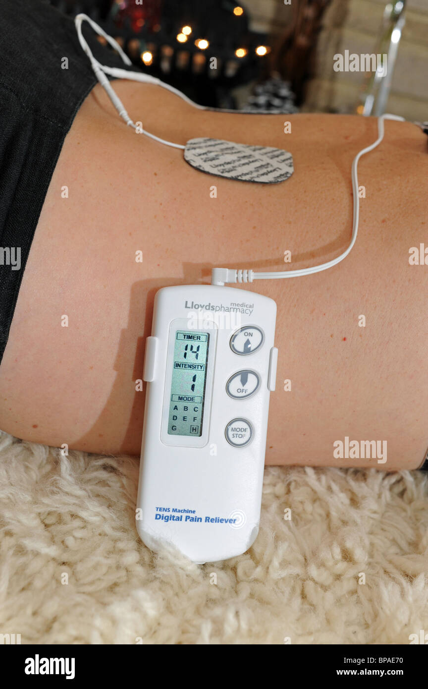 Woman female using a Lloyds Pharmacy TENS Digital Pain Reliever to help