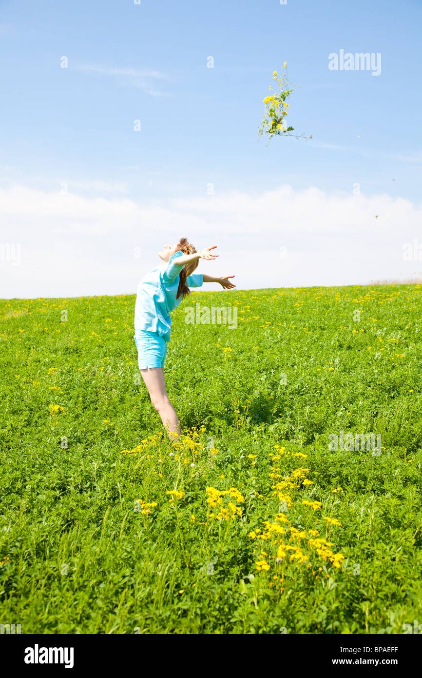 Young woman throwing flowers on a grass field. Stock Photo
