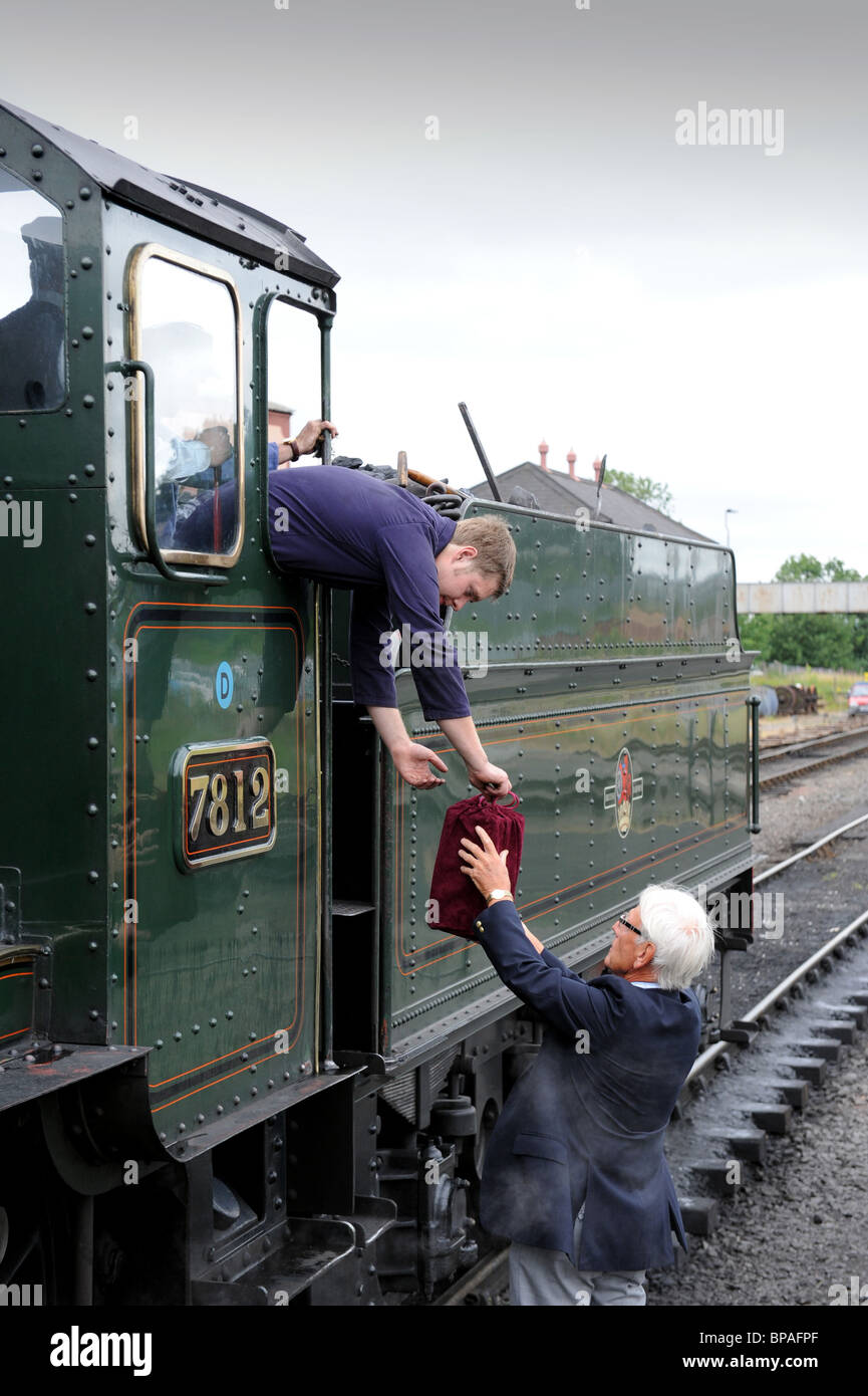 Man hands over urn containing human ashes to the driver of Severn Valley Railway steam engine Stock Photo