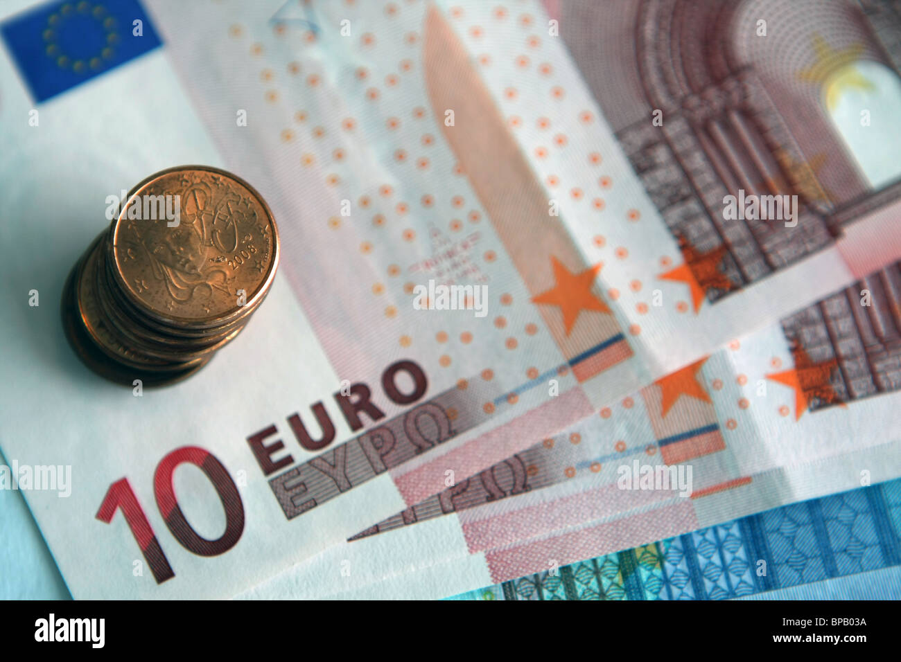 A stack of 5 cent and 1 cent euro coins on a mixture of 10 and 20 euro notes Stock Photo