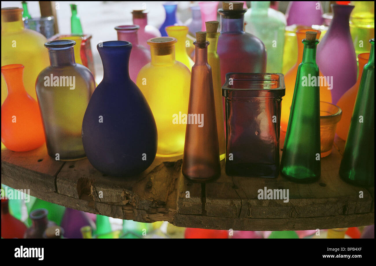 Close-up of vividly colored, translucent, bottles with corks displayed on weathered wooden table. Stock Photo