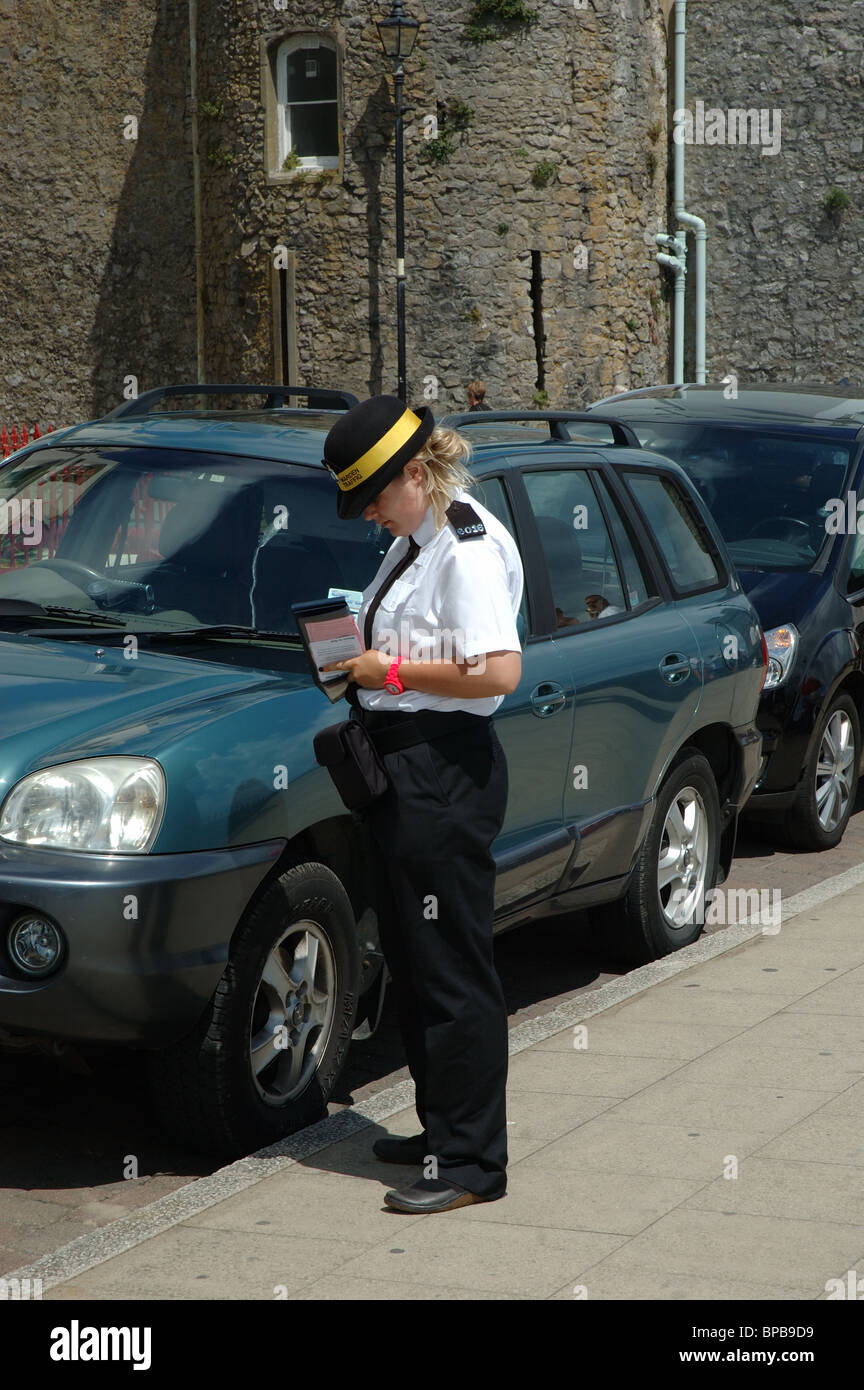 female traffic warden writing out a parking ticket, Tenby, Wales, UK Stock Photo