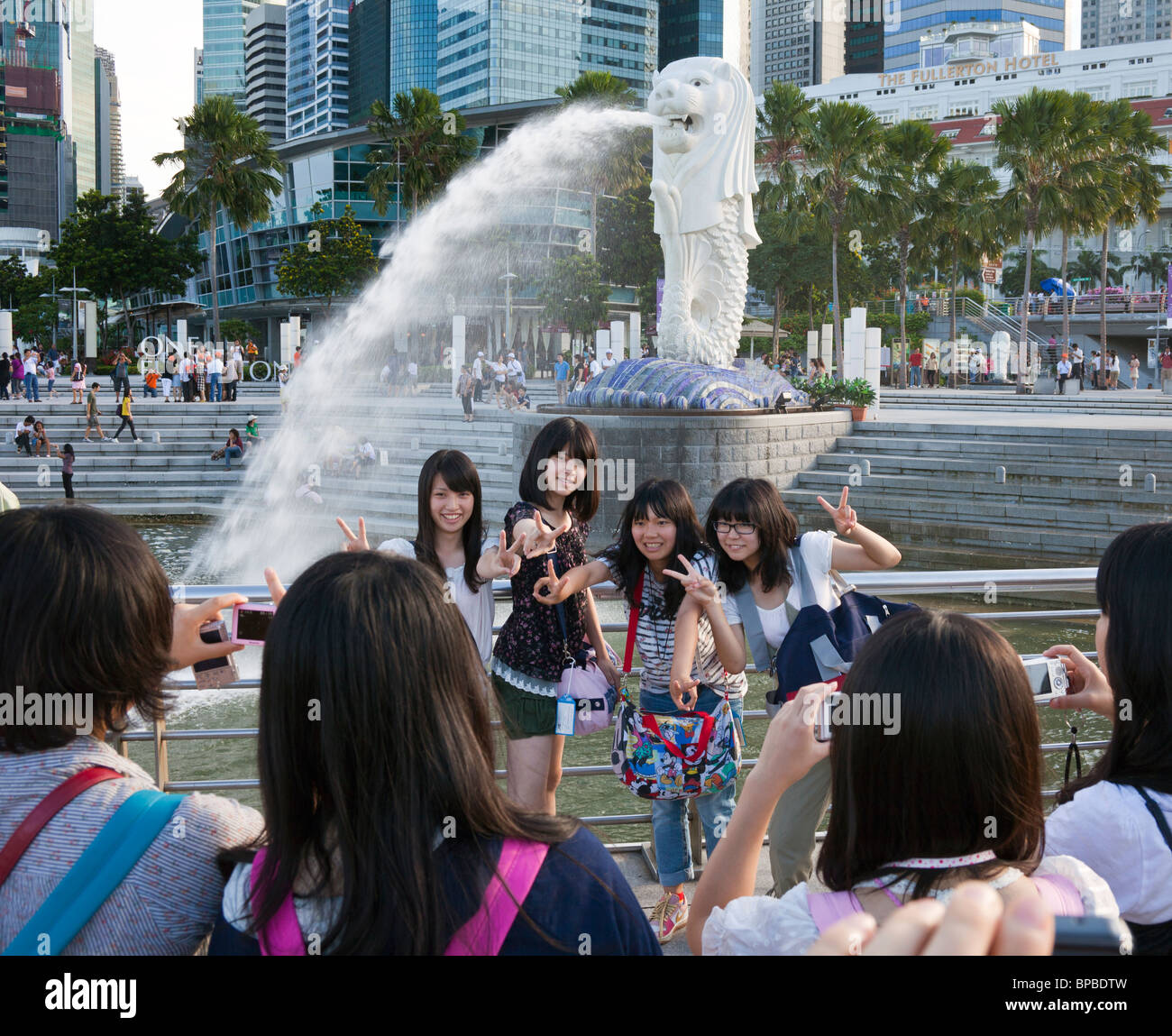 Chinese tourists taking photographs in front of the merlion, the symbol of Singapore Stock Photo