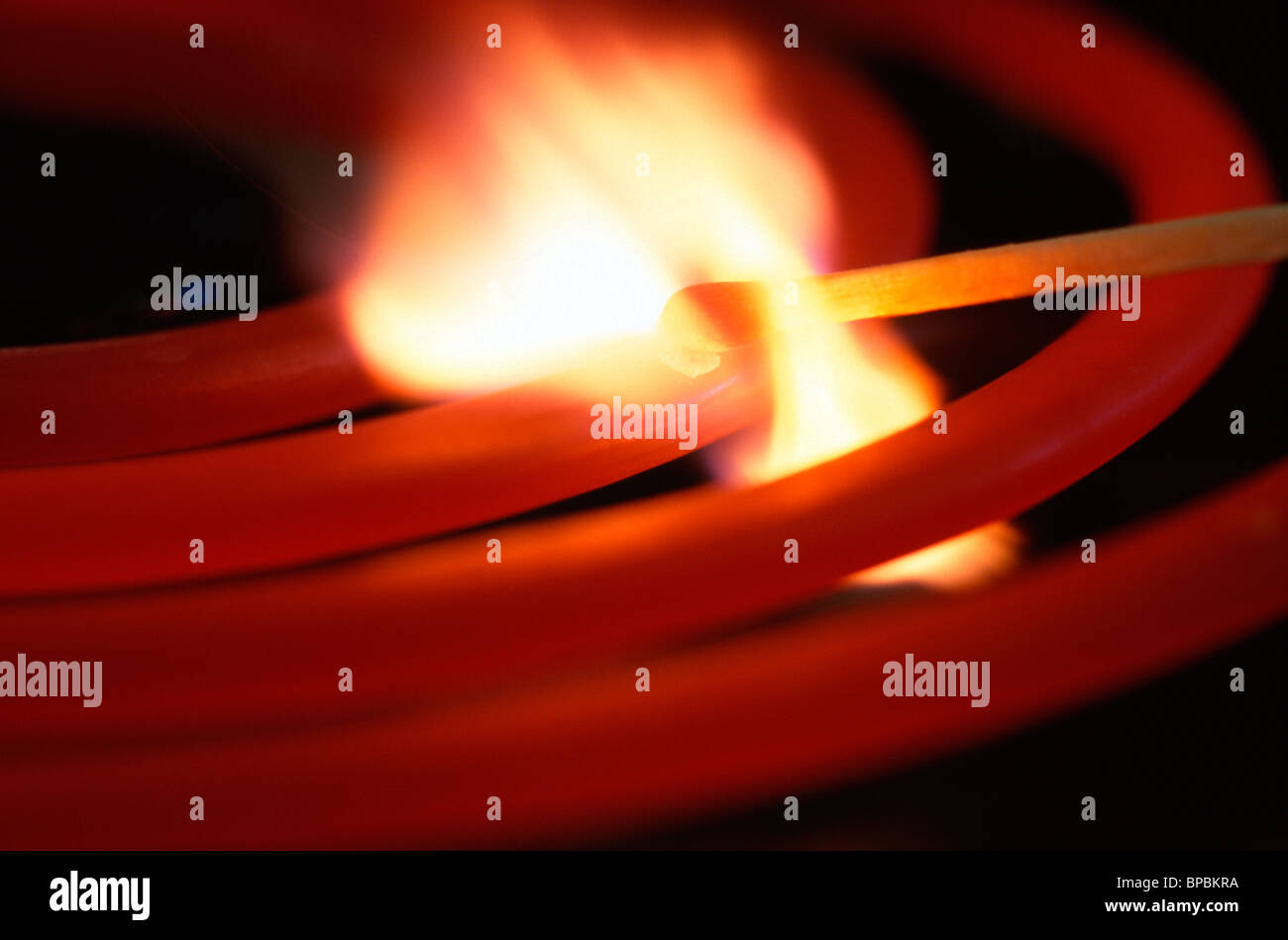 Wooden match bursts into flame on electric stove element. Stock Photo