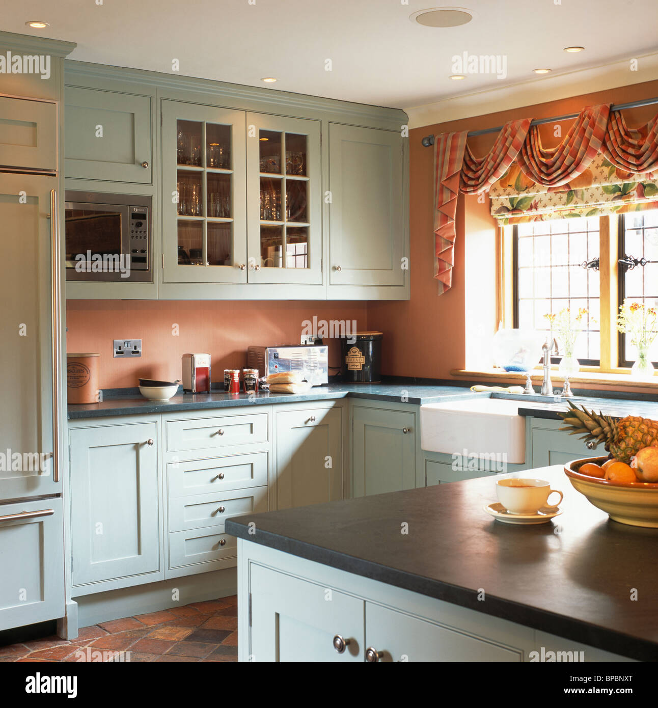 Pastel blue fitted units with granite worktops in terracotta