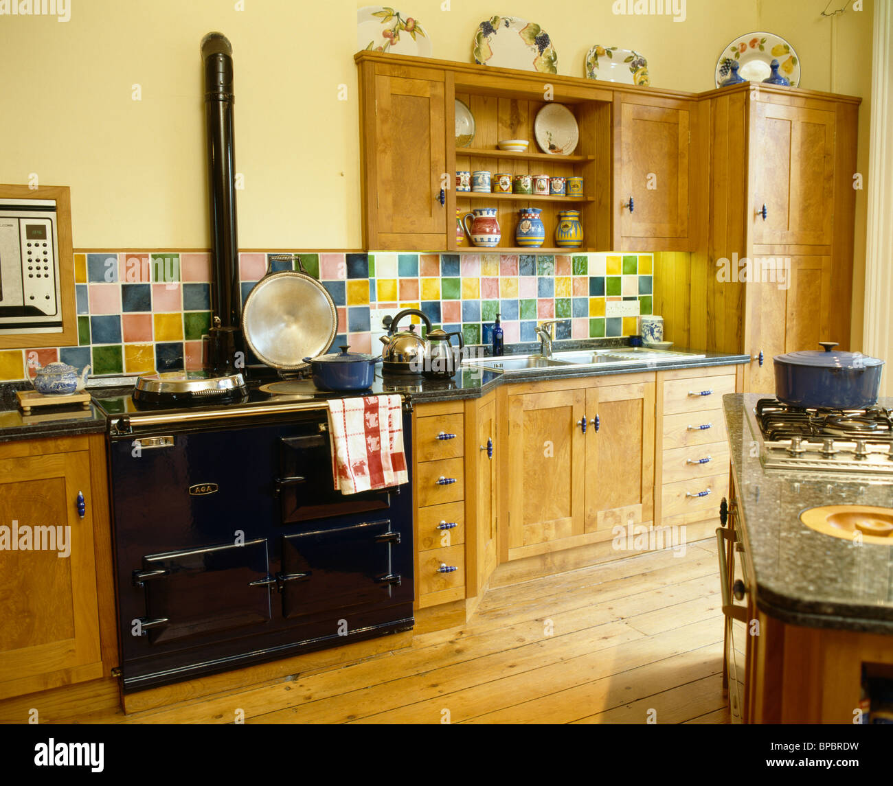 Colorful ceramic tiled splashback on wall above Black Aga oven in