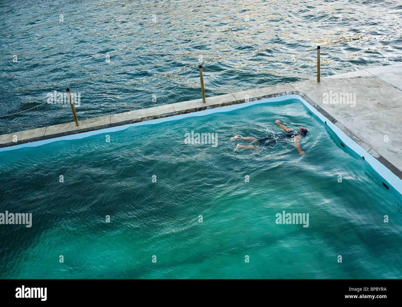 A swimmer floating and snorkeling in a seaside pool. Stock Photo