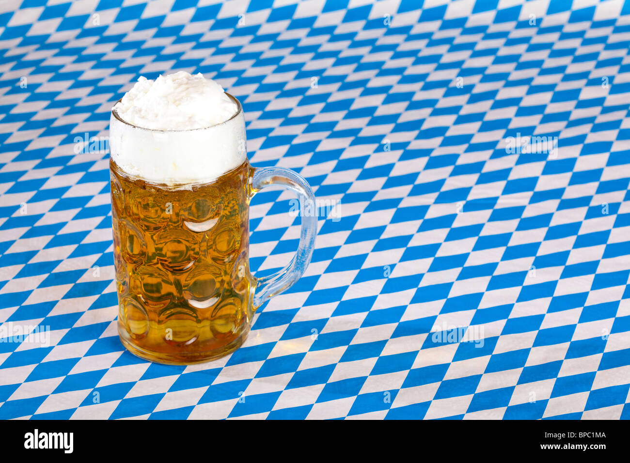 Oktoberfest beer stein with copy space and Bavarian flag in background. Stock Photo