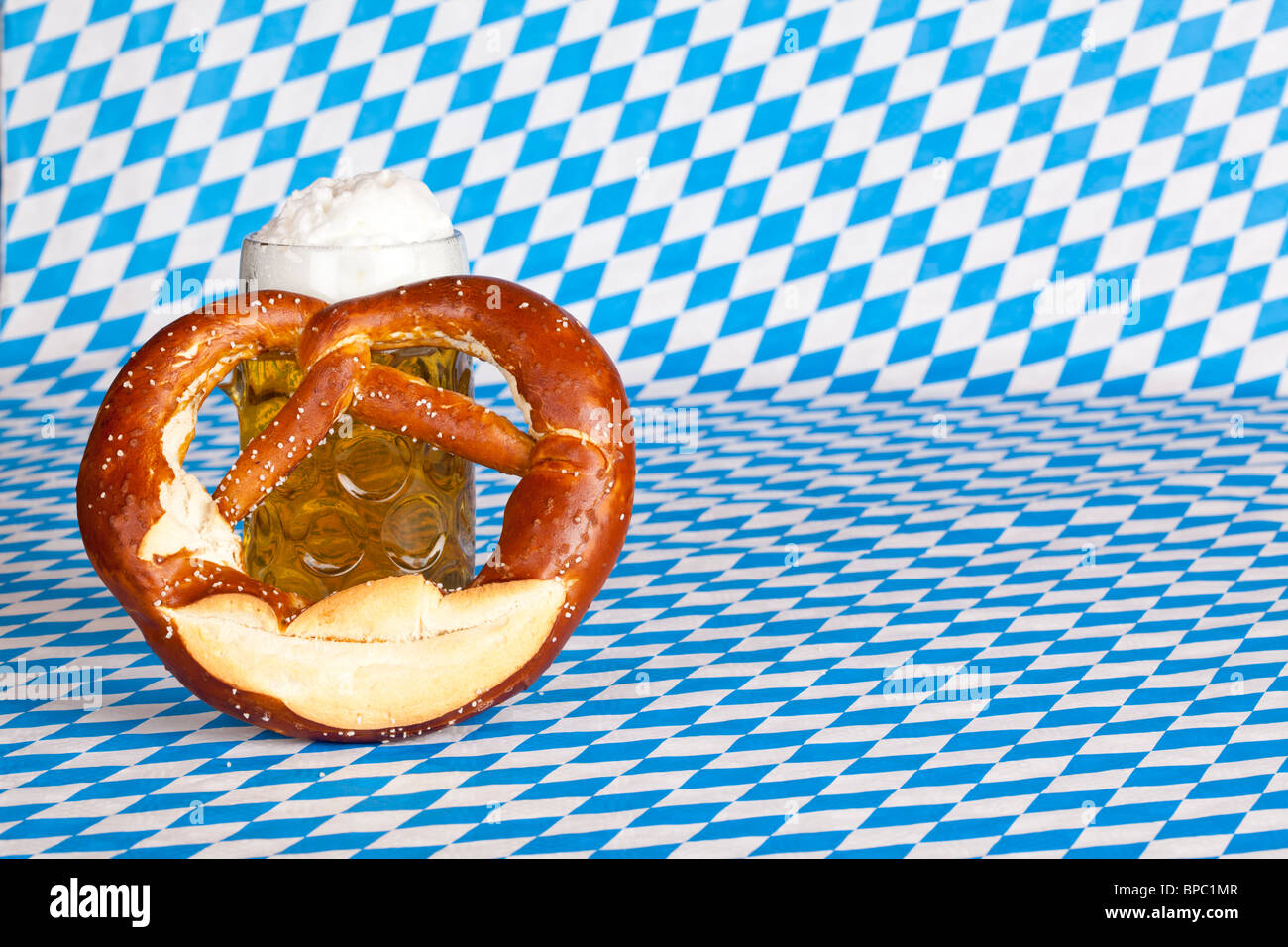 Oktoberfest beer stein with pretzel and Bavarian flag in background Stock Photo