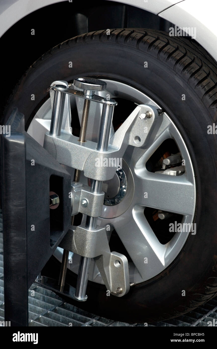 Car wheel fixed with computerized wheel alignment machine clamp. Closeup of repairshop equipment. Stock Photo