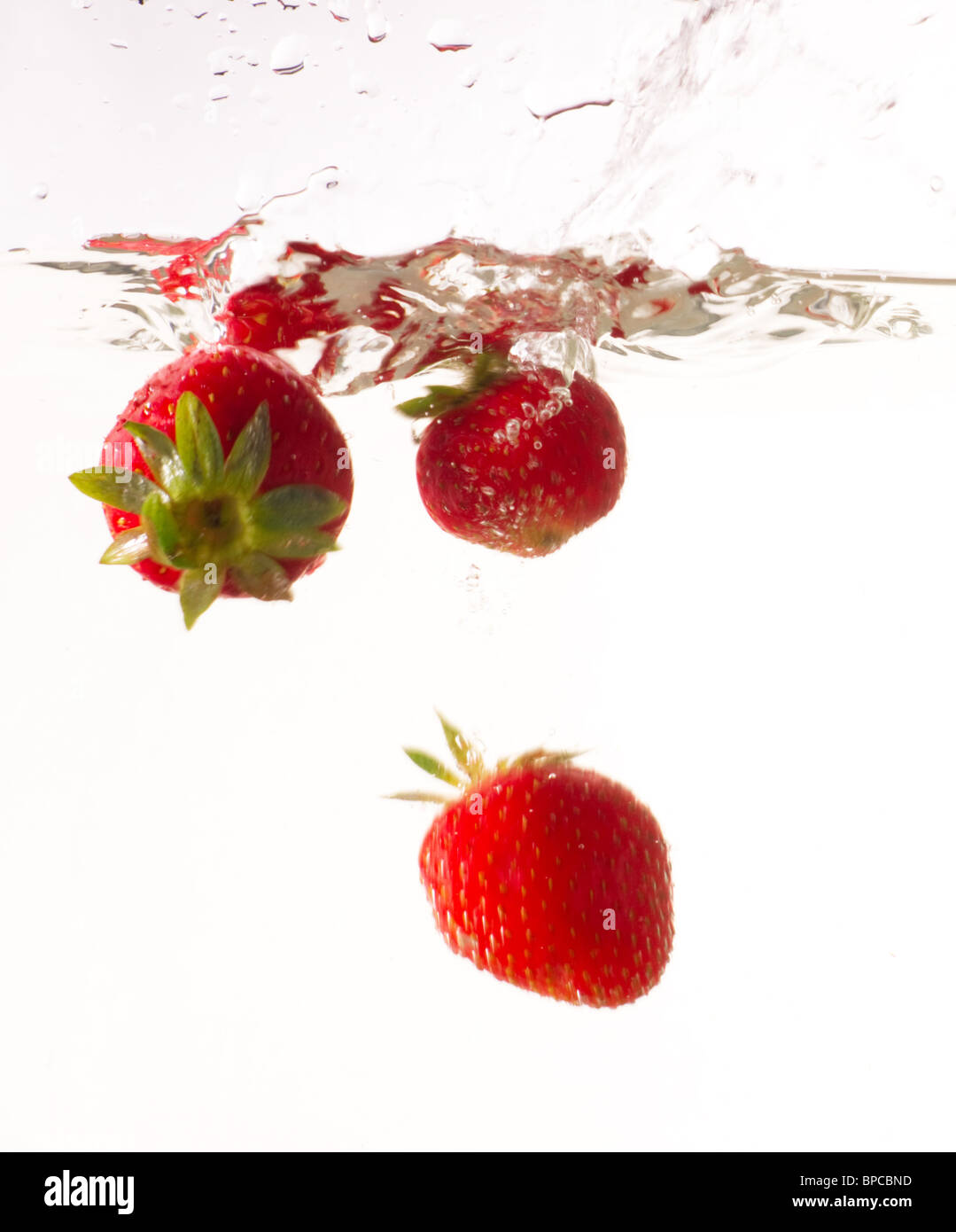 Several Strawberries drop into the water with a splash Stock Photo - Alamy
