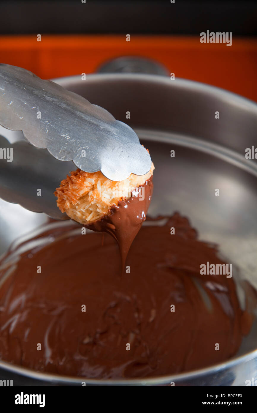 Dipping macaroon into melted chocolate Stock Photo