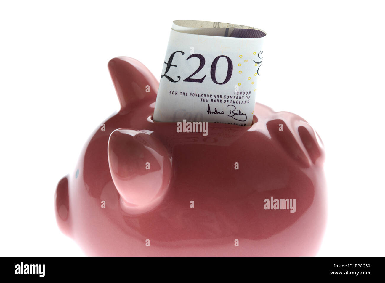 pink piggy bank with 20 pound note on white background Stock Photo