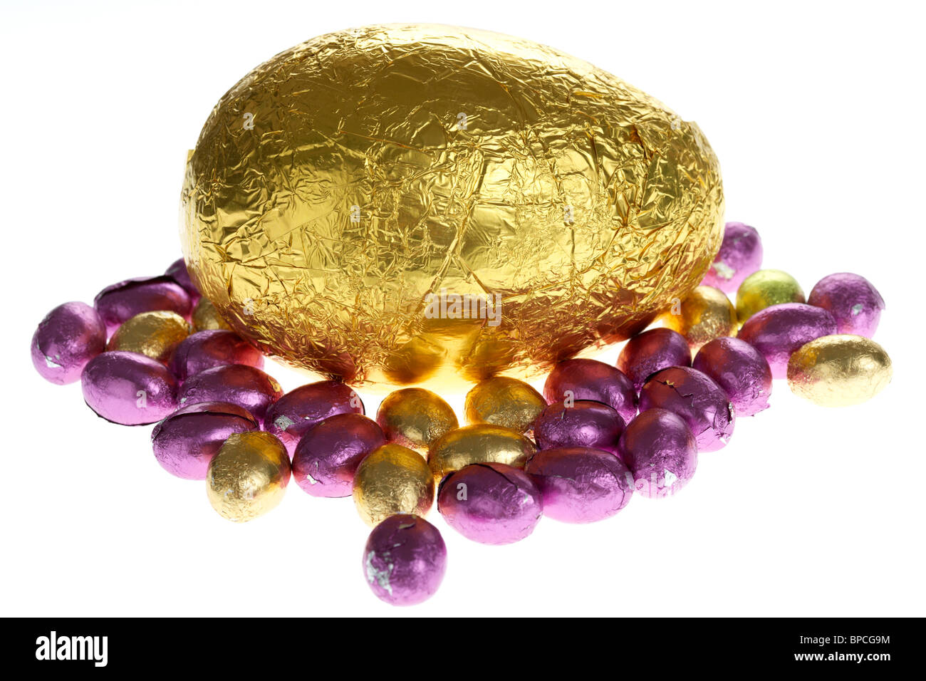 large and small gold foil wrapped chocolate easter eggs on white Stock Photo