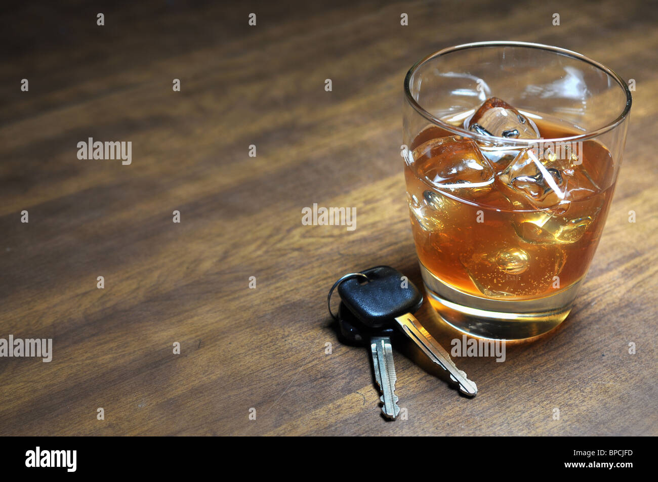 Glass of whiskey and car keys on wooden table. Stock Photo