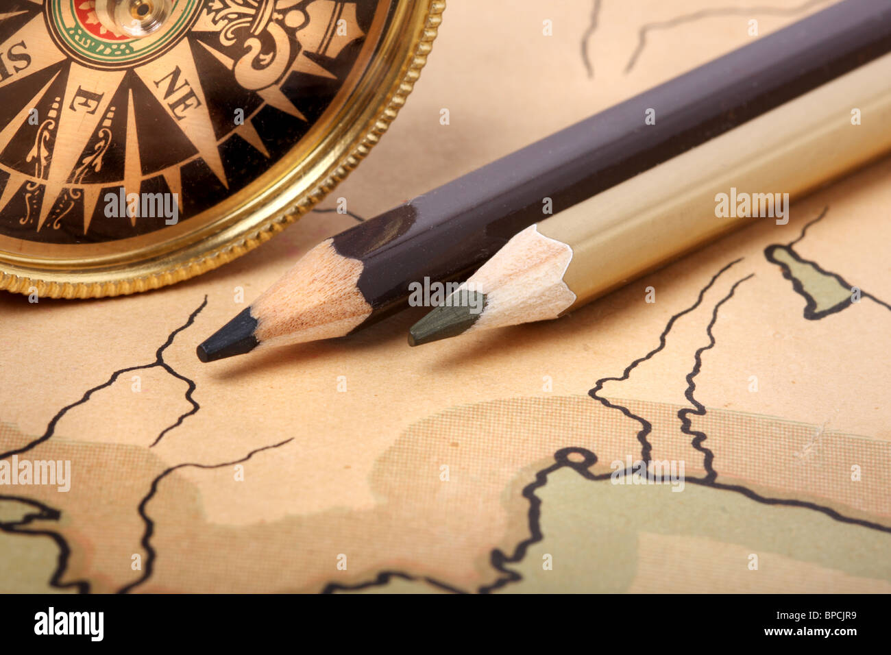 Compass and pencils on old contoured map, shallow DOF Stock Photo