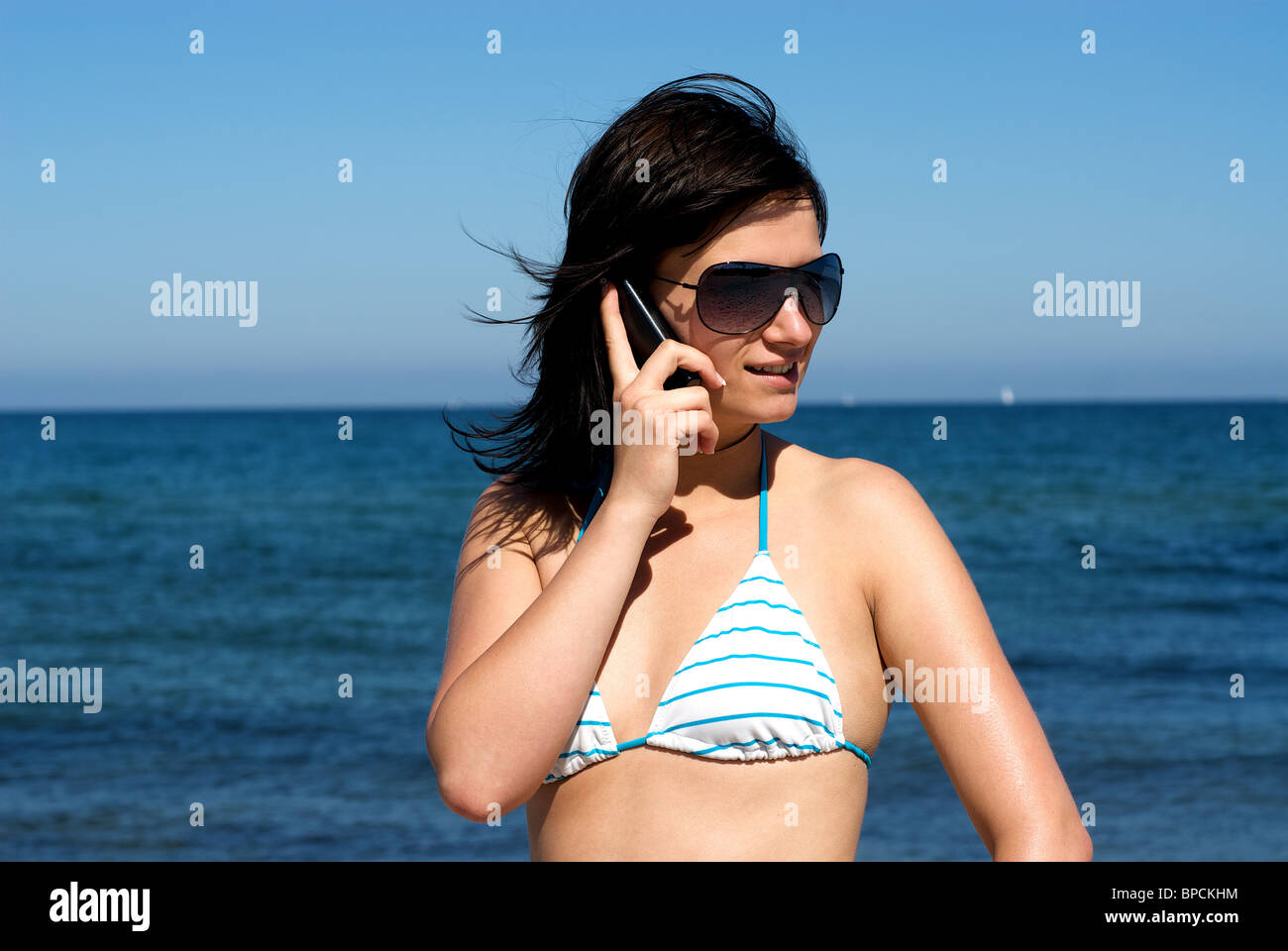 A young woman speaking on the phone on a beach Stock Photo