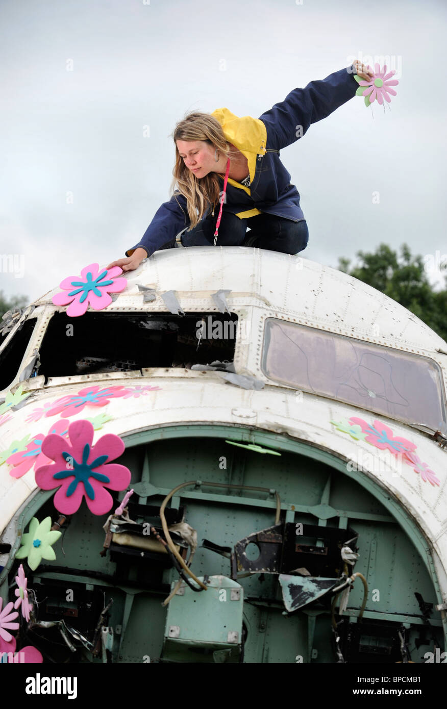 An artist decorates an old RAF plane with flowers in The Trash City area at the Glastonbury Festival site Pilton UK Stock Photo