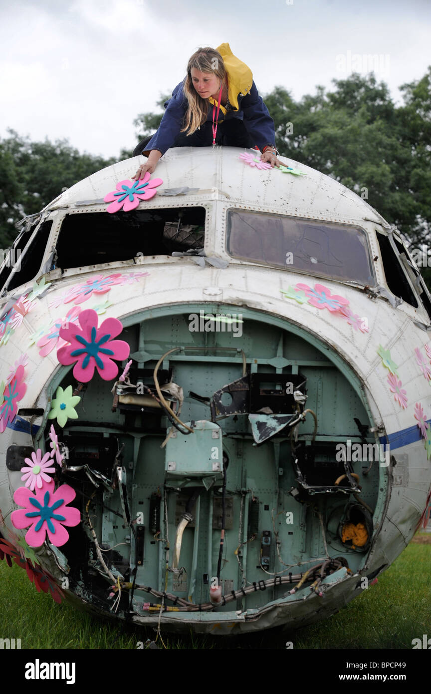 An artist decorates an old RAF plane with flowers in The Trash City area at the Glastonbury Festival site Pilton UK Stock Photo