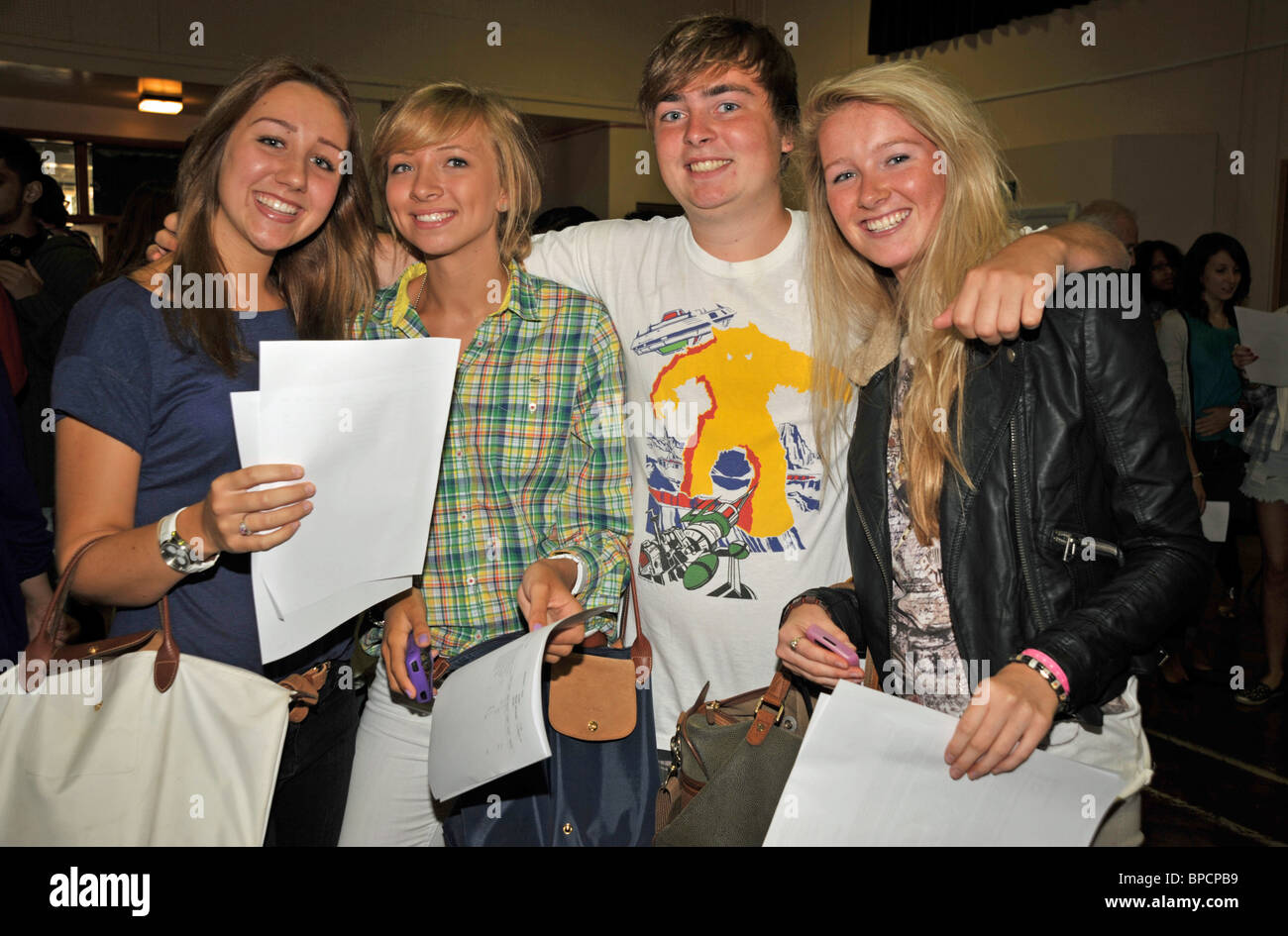 A group of four smiling A level students posing to camera in their school hall Stock Photo