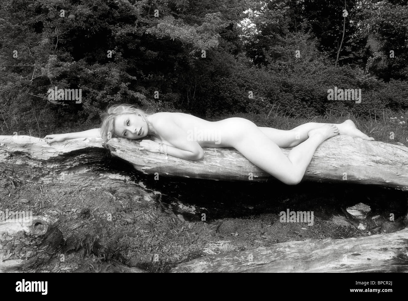 naked woman on tree trunk Stock Photo