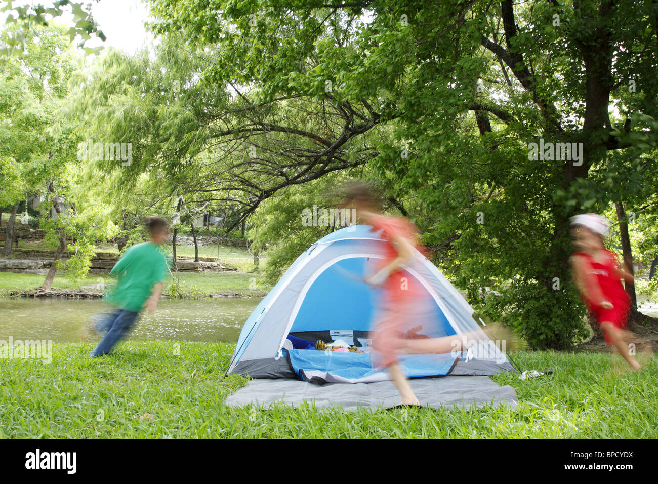Kids chasing each other around a tent while camping Stock Photo