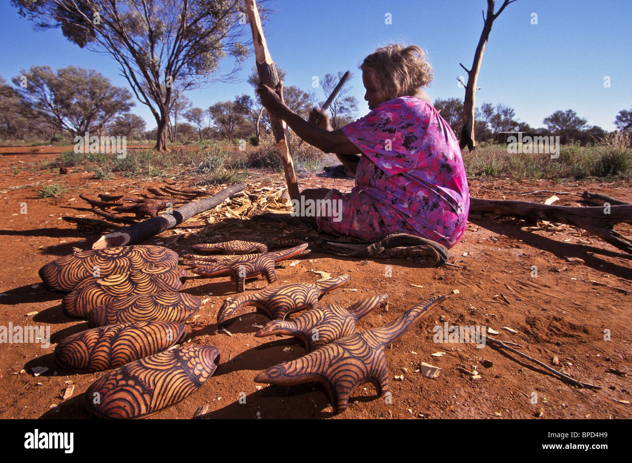 Senior Anangu woman preparing wood for carving, South Australia Stock