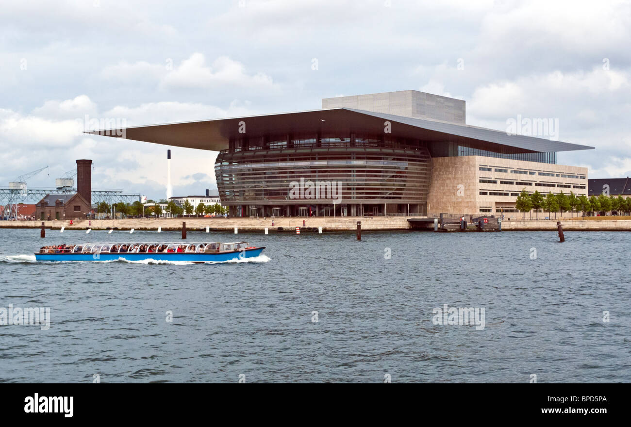 The Royal Opera House on Holmen in Copenhagen Denmark with a harbour cruising vessel passing by. Stock Photo