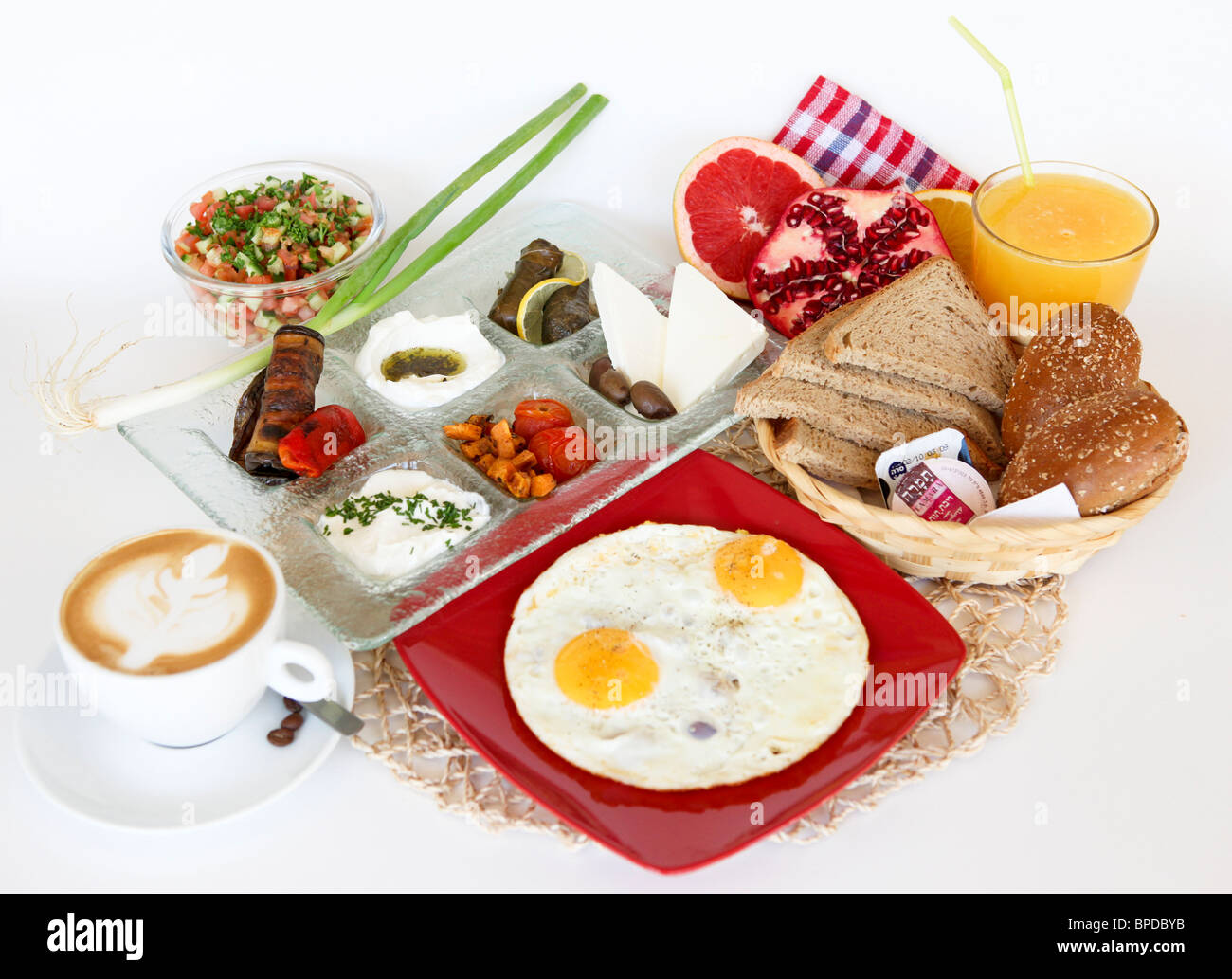 Traditional Israeli Breakfast with two fried eggs, cheeses, salad, a fresh roll orange juice and a cup of cappuccino Stock Photo