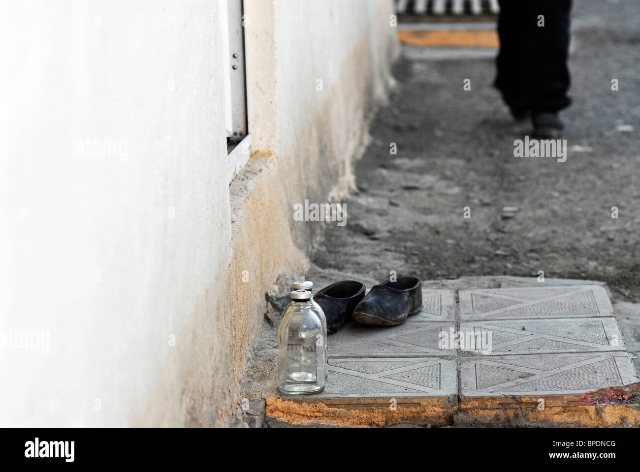 Azerbaijan, Xinaliq, low section view of person walking with pair of shoes and bottle Stock Photo