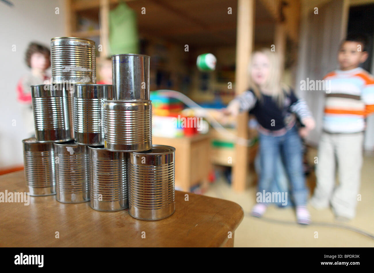 Children throwing balls at empty tins during a birthday party, Berlin, Germany Stock Photo
