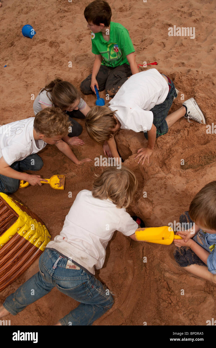 A group of six 6 young children kids having fun playing digging in sandpit at National Eisteddfod of Wales Ebbw Vale 2010 Stock Photo