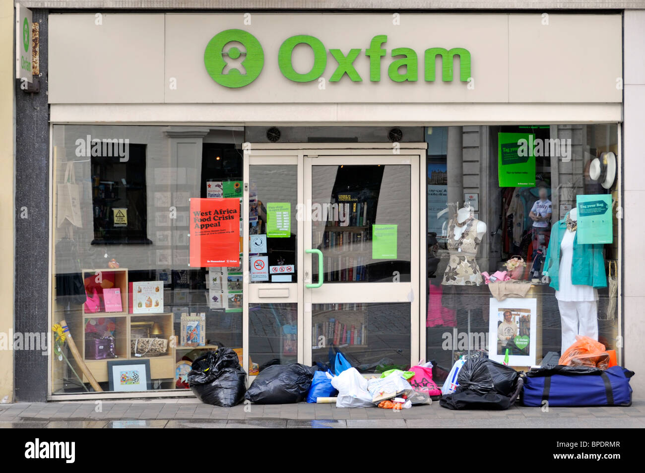 Donations left on pavement outside Oxfam shop window & entrance door before opening time High Street Brentwood Essex England UK Stock Photo