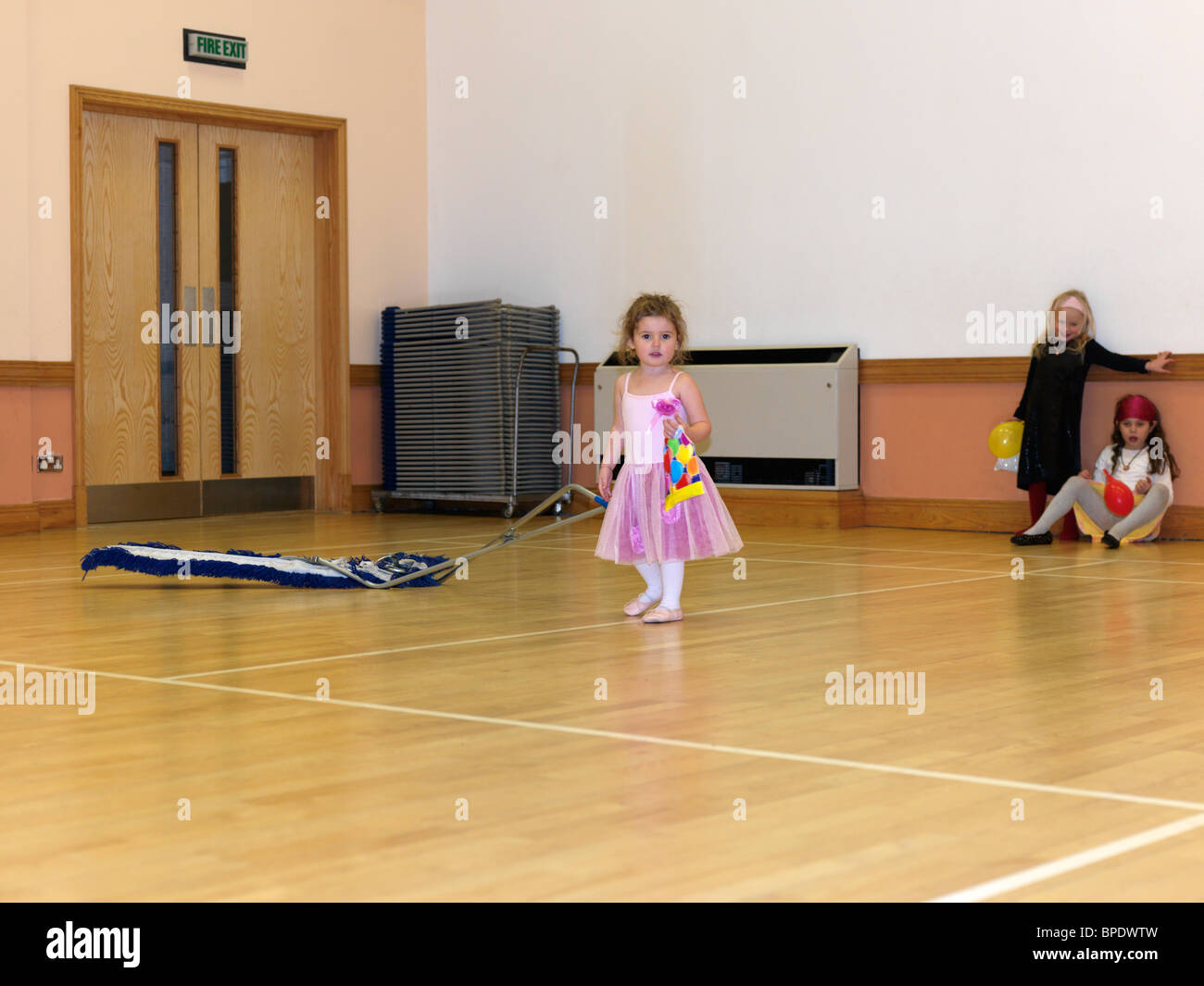 Young Girl Pulling Sweeper In A Hall After A Party Stock Photo - Alamy