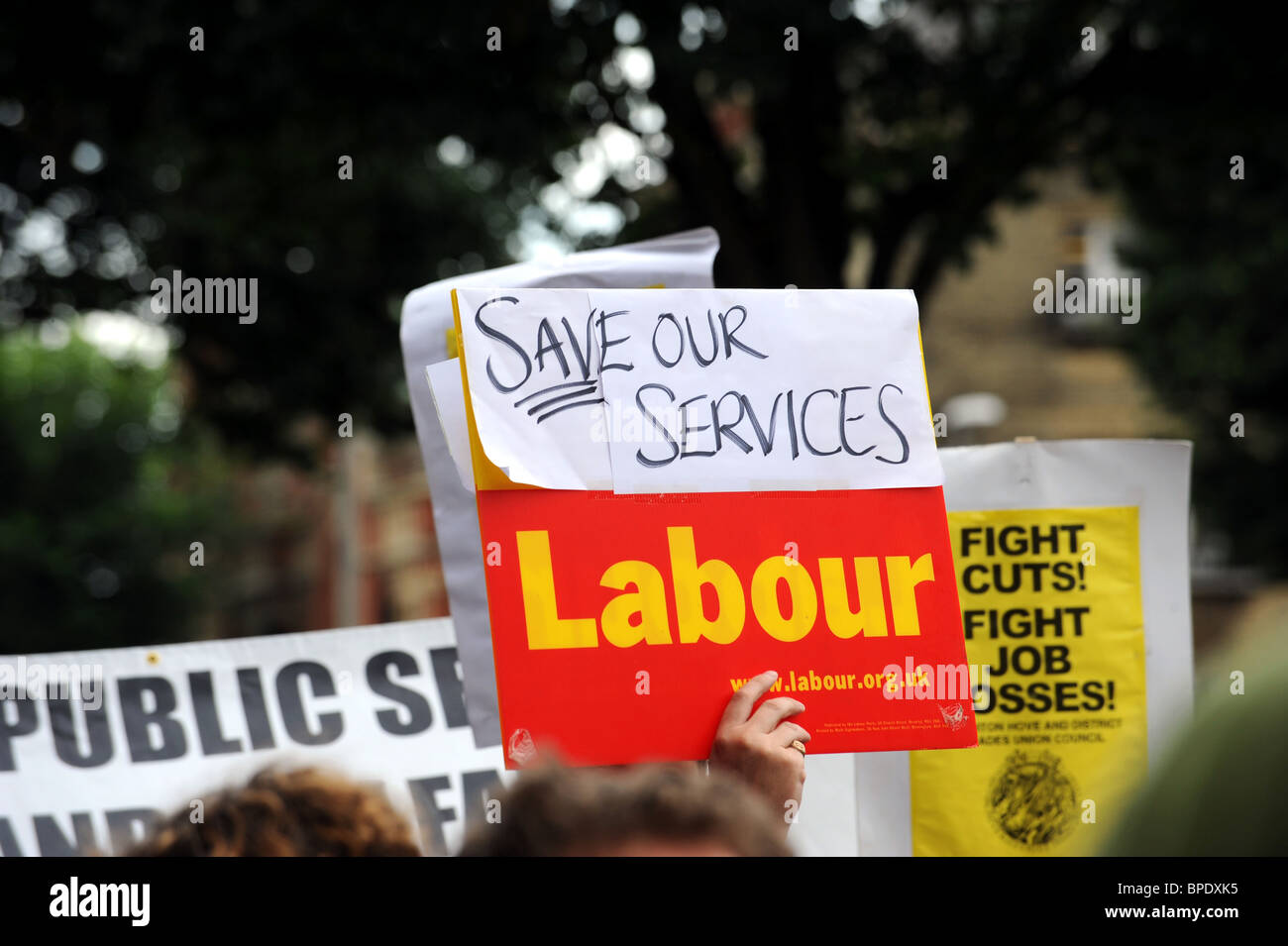 A man holds up a save our services in a protest about upcoming cuts to be made by the new coalition government Stock Photo