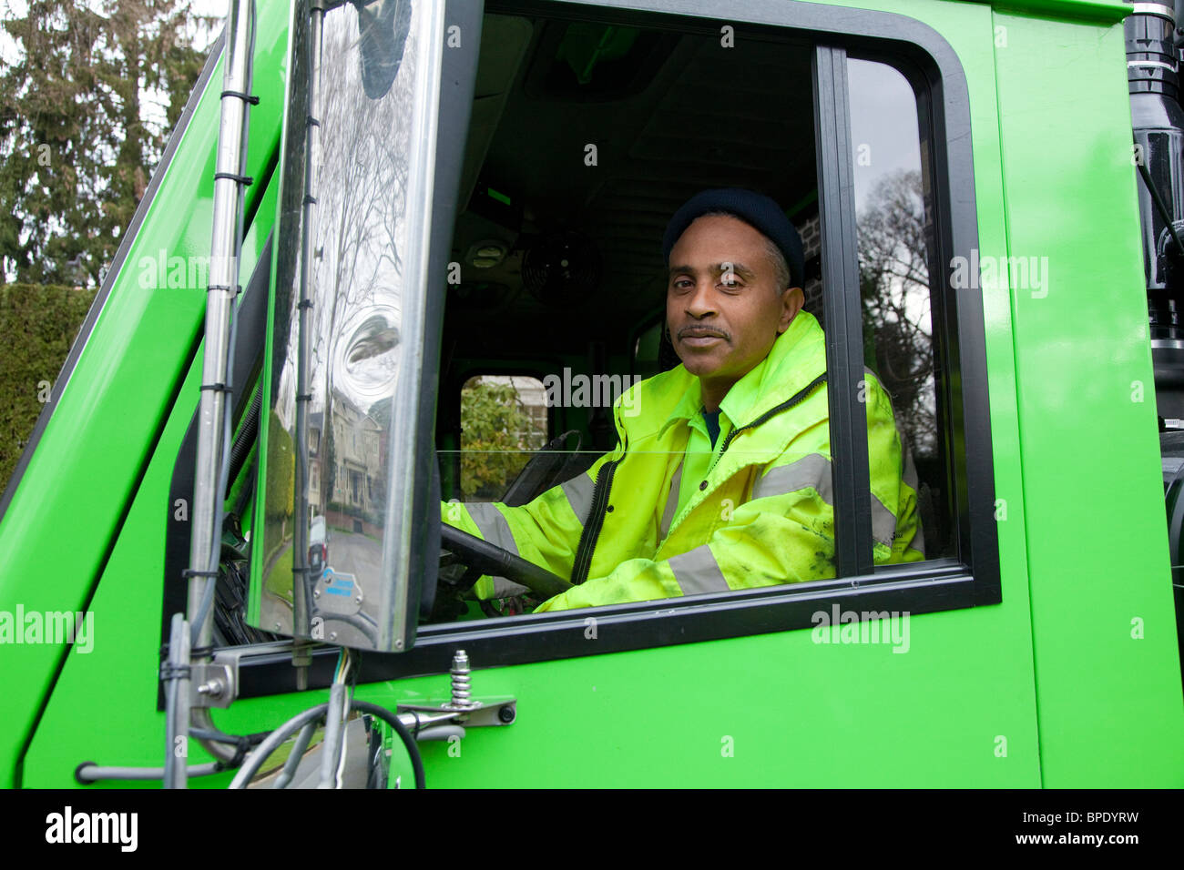 African American man driving garbage truck Stock Photo