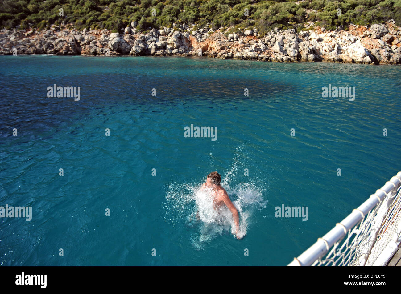 A male tourist jumps off a boat straight into the Aegean sea during a pleasure cruise round Kalkan Stock Photo