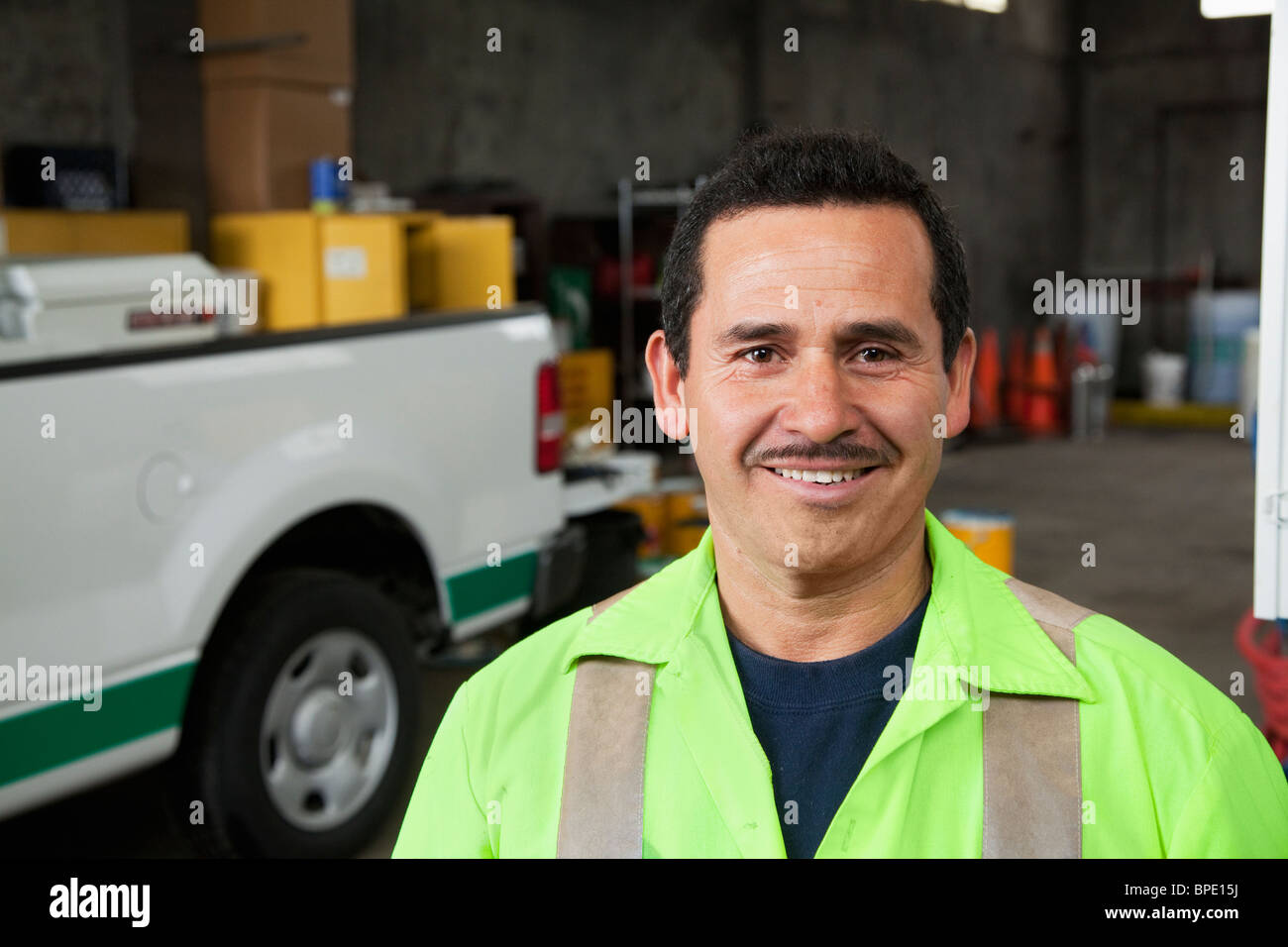 Hispanic sanitation worker smiling in garage Stock Photo