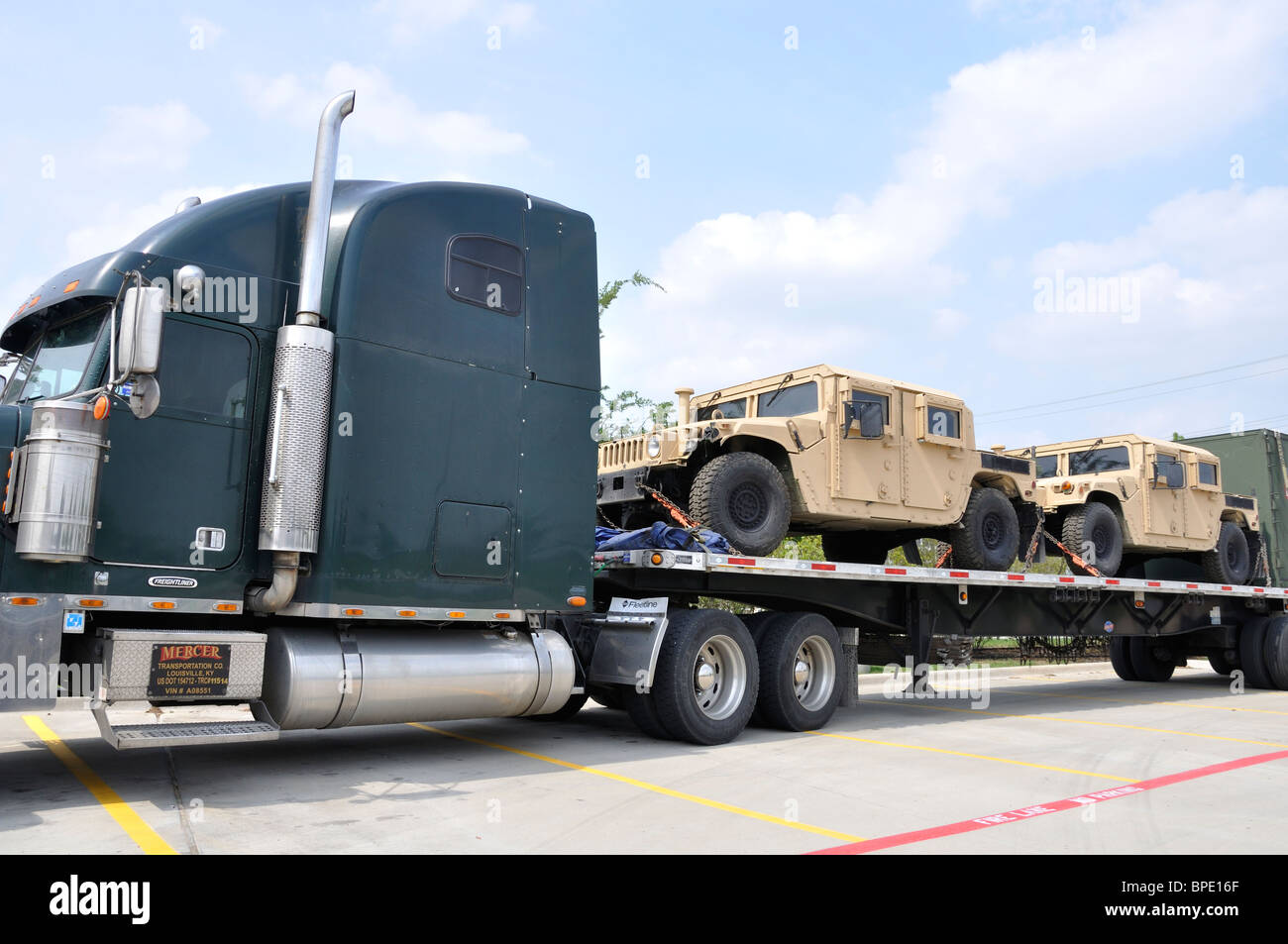 US military trucks being transported on large truck Stock Photo