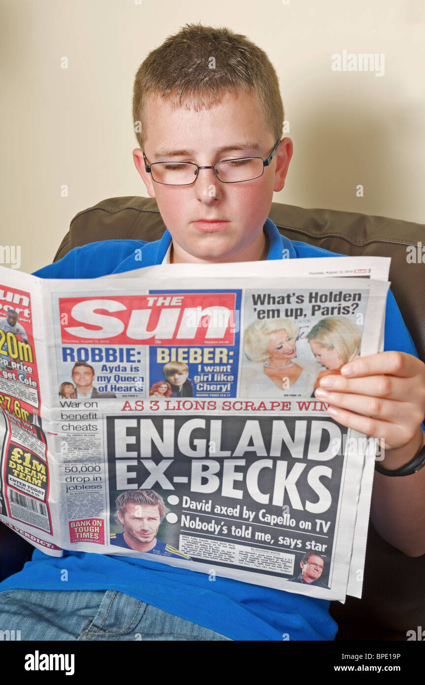 Teenager reading a copy of The Sun newspaper Stock Photo