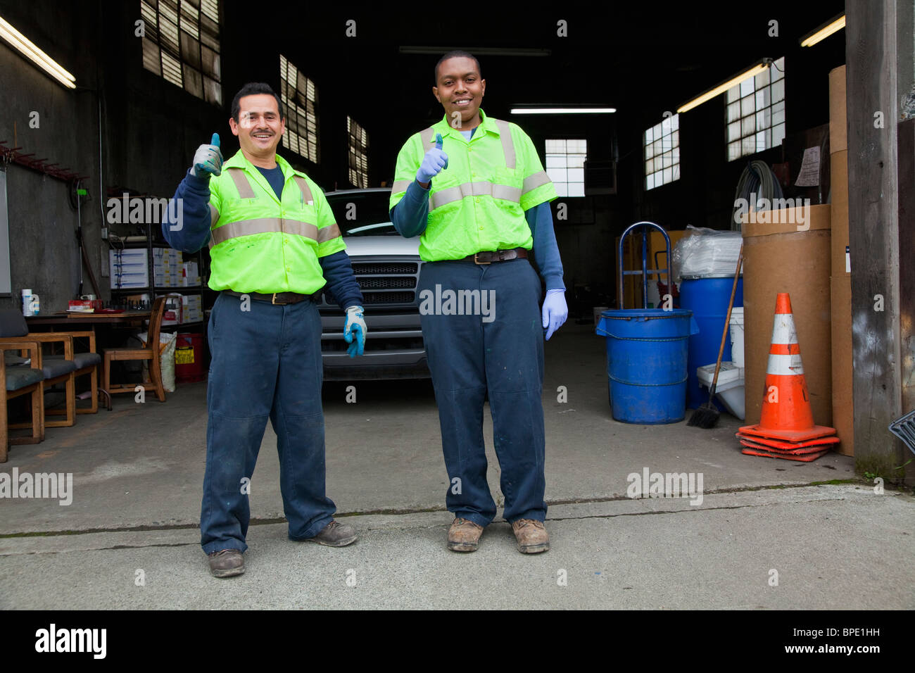 Sanitation workers giving thumbs up in garage Stock Photo