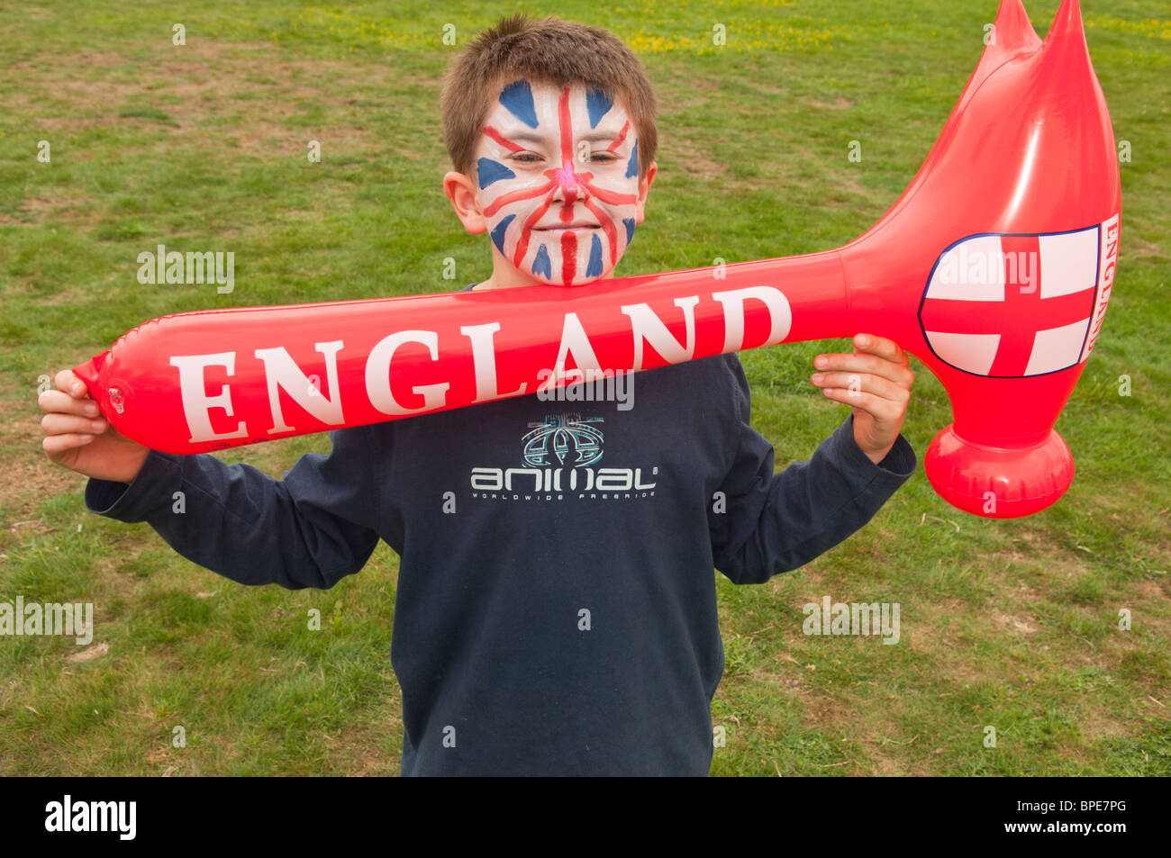 A MODEL RELEASED 10 year old boy with his face painted as an England union jack flag holding an inflatable hammer in the Uk Stock Photo