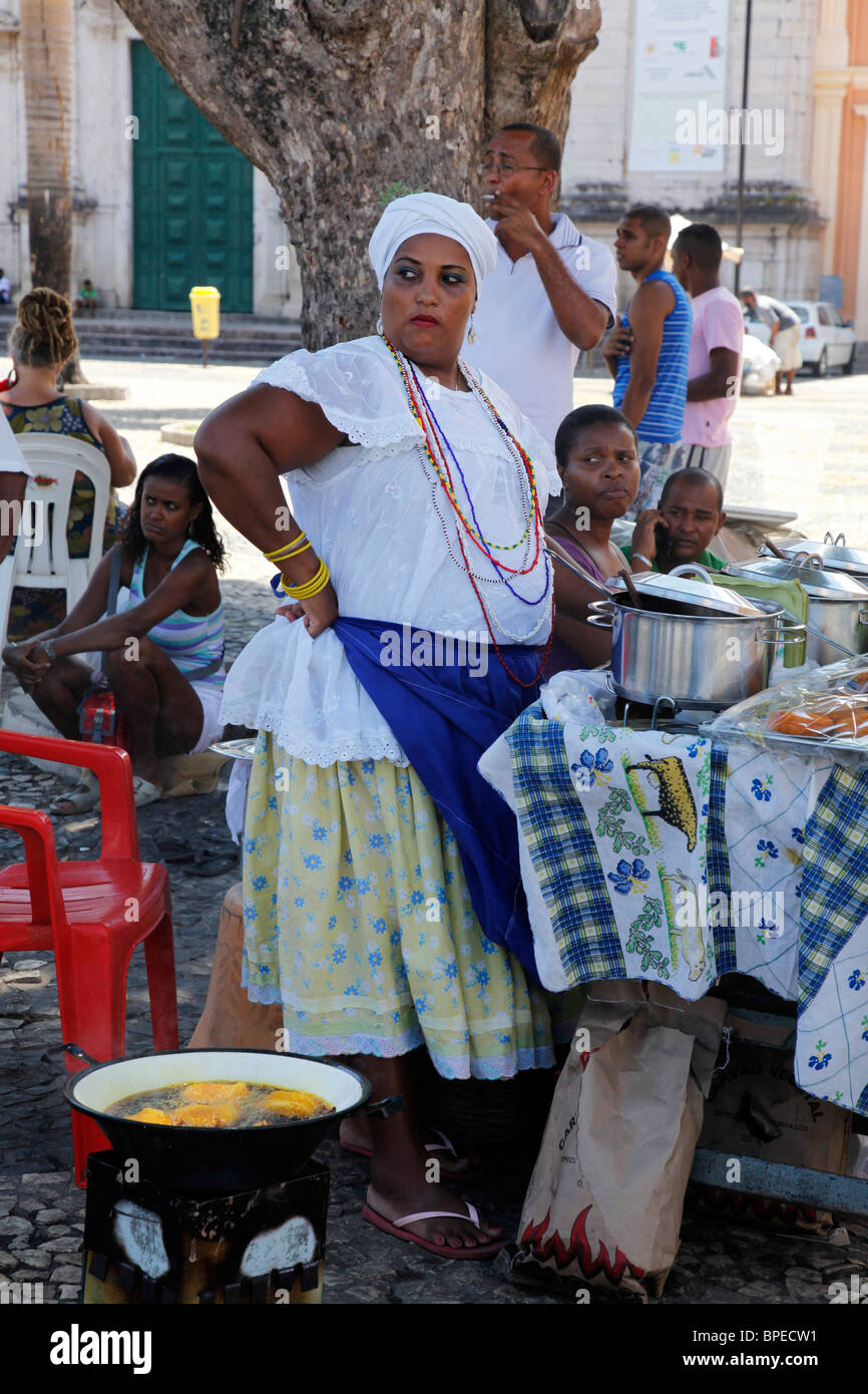 Bahian woman in traditional white dress (Baiana) selling street food at the Pelourinho district, Salvador, Bahia, Brazil. Stock Photo