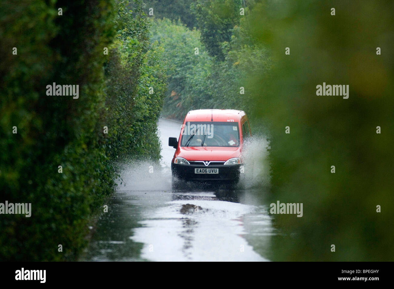 Postal Service van driving through flooded country lanes in the Murton district of Swansea today during the heavy downpours. Stock Photo