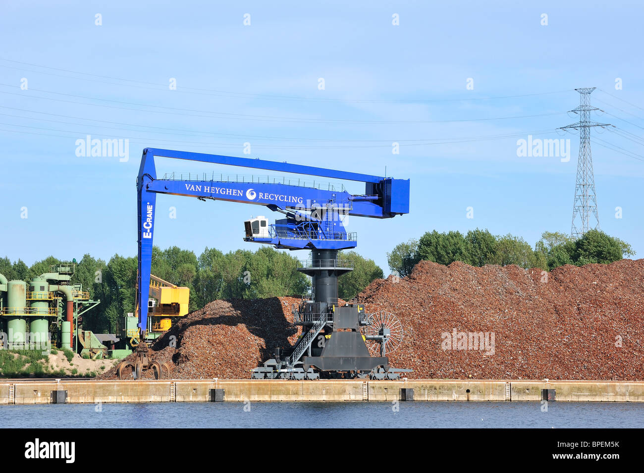 Dock crane and scrap heap along the Ghent-Terneuzen Canal at Ghent seaport, Belgium Stock Photo
