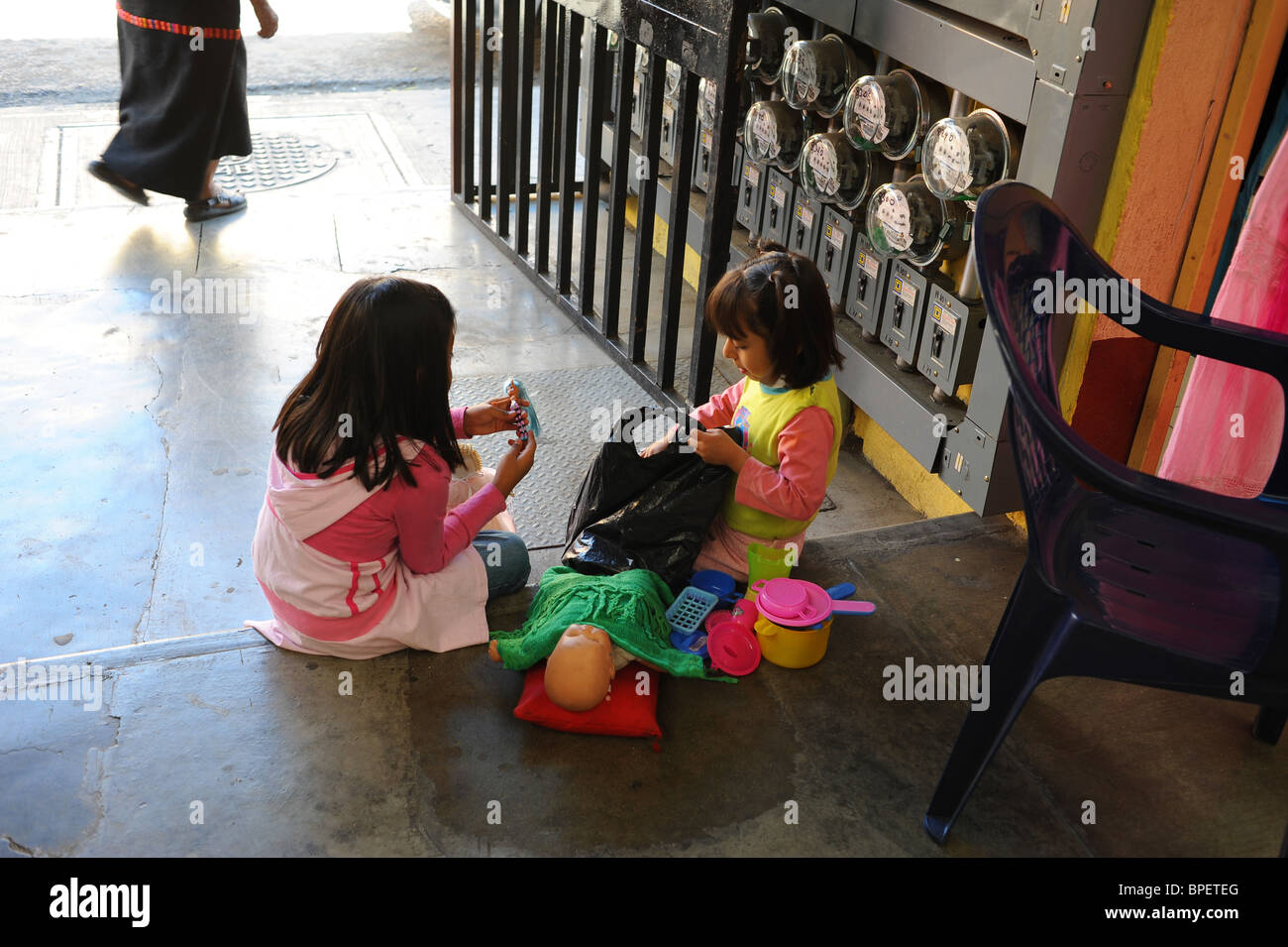 Two girls 5-6 years play with doll in entrance to market. Oaxaca, Mexico. Stock Photo