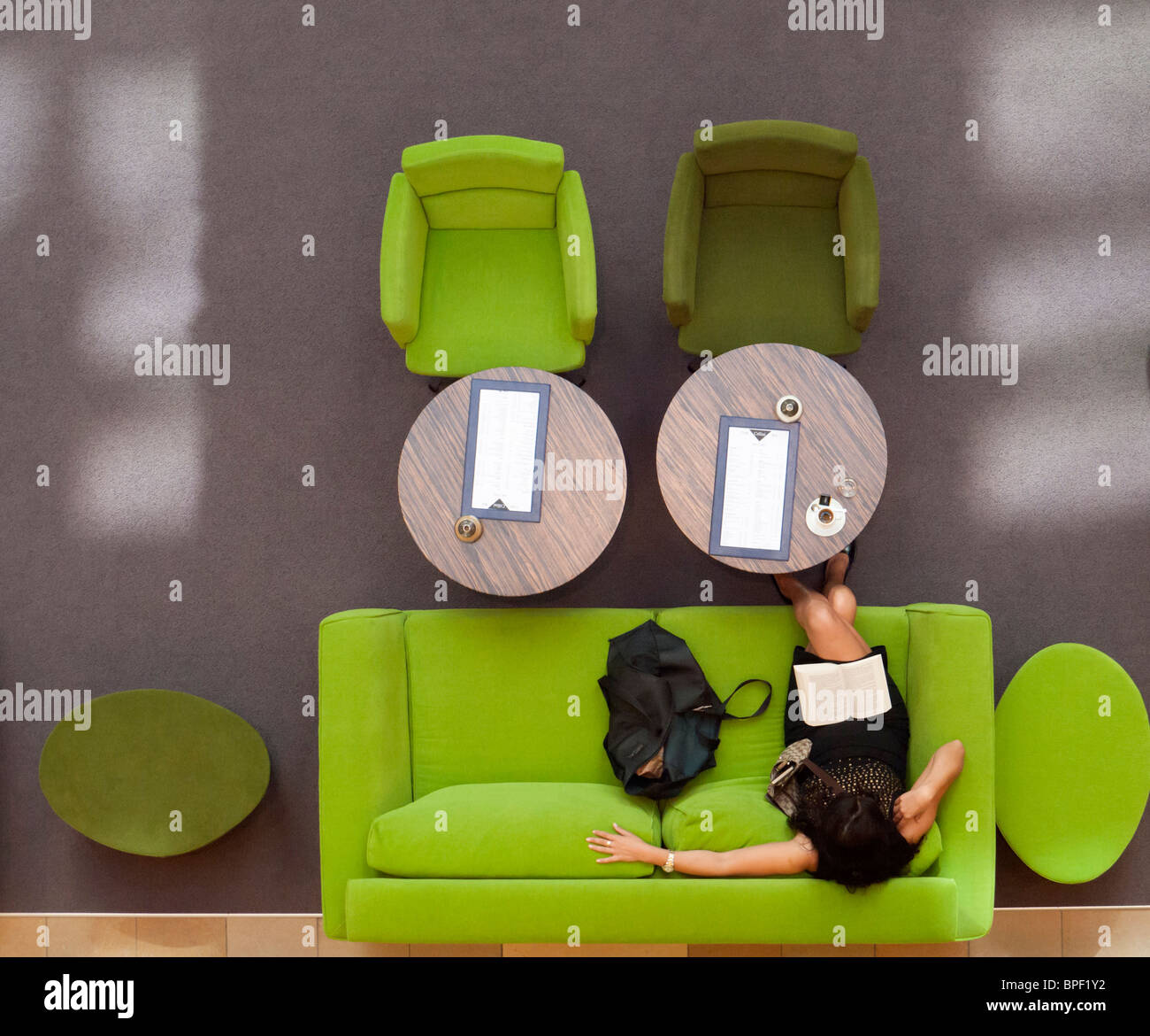 Woman reading on colorful sofa inside upmarket shopping mall on Friedrichstrasse in Berlin Germany Stock Photo